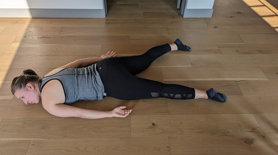Photo of a depressed looking woman in yoga pants lying face down on the floor