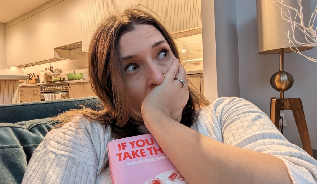 Picture of a woman reclining in a chair with a pensive look on her face, cradling her own book to her chest.